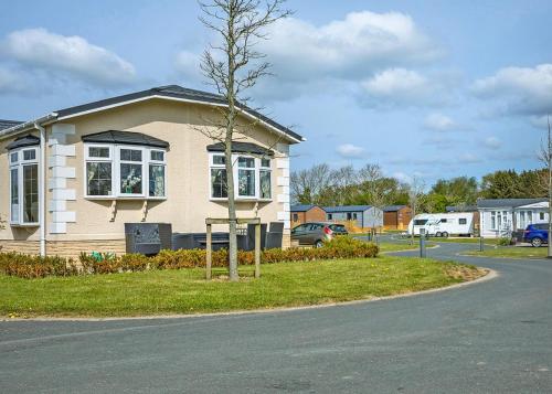 a small house with a tree in front of it at Cleveland Hills View Holiday Park in Middleton upon Leven