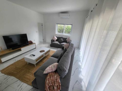 a living room with a couch and a tv at Te Aro Villa in Muri 1 &2 in Rarotonga