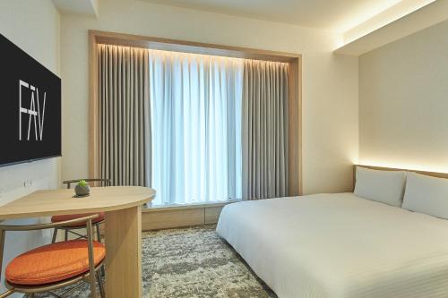 a bedroom with a bed and a table and a window at FAV LUX Kagoshima Tenmonkan in Kagoshima