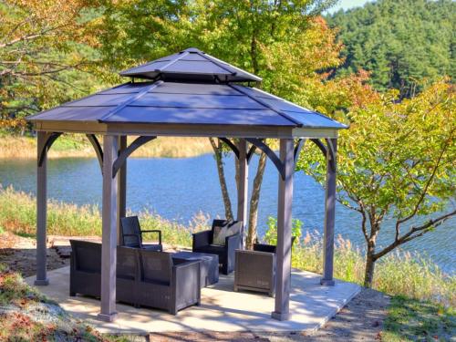 a gazebo with chairs in front of a lake at Ashiwada Hotel in Fujikawaguchiko