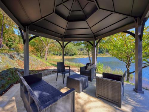 a gazebo with chairs and tables and a lake at Ashiwada Hotel in Fujikawaguchiko