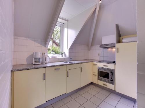 a kitchen with white cabinets and a sink and a window at Detached Home in Netherlands with Garden in Dalfsen