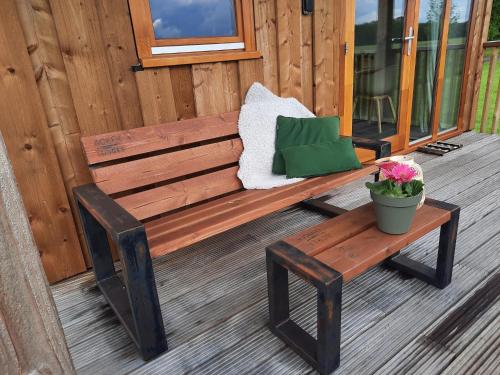 a wooden bench sitting on a porch with a potted plant at Lodge by Dutch Meadows with Scenic Veranda in Ruinerwold