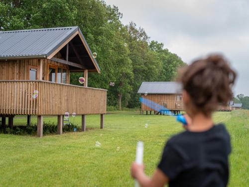 a young girl flying a kite in front of a house at Lodge by Dutch Meadows with Scenic Veranda in Ruinerwold