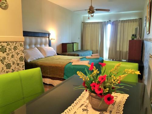Un dormitorio con una cama y una mesa con flores. en Departamentos Sobre el Mar, en Villa Gesell