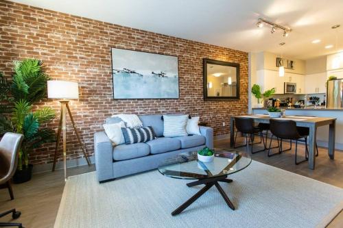 a living room with a blue couch and a brick wall at 3 Miles to Disney Heated Pool CnvntnCtr Jacuzzi in Fullerton