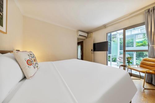 a bedroom with a white bed and a large window at 6號花園別墅酒店 Shenzhen No'6 Garden Villa --French Window with garden view,Close to Sea World &Shekou Ferry Port &K11 Ecoast &Subway Nearby ,Offer Western food and coffee &English speaking with tour services in Shenzhen