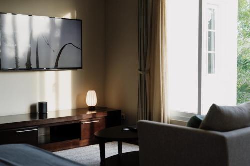 a living room with a couch and a tv on the wall at Kula Kara Villas Uluwatu in Uluwatu