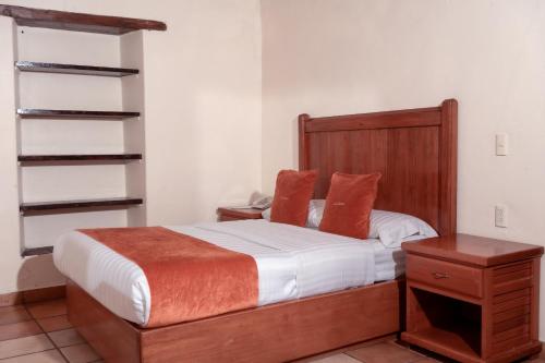 a bedroom with a bed with a wooden headboard and a table at Hotel La Casona in Jilotepec de Abasolo