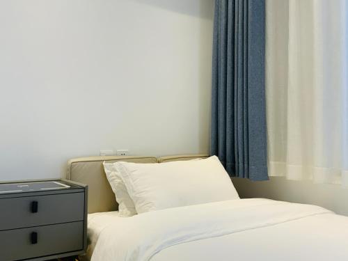 a bedroom with a bed and a dresser with a white bedsheet at 叁三民宿 in Dali