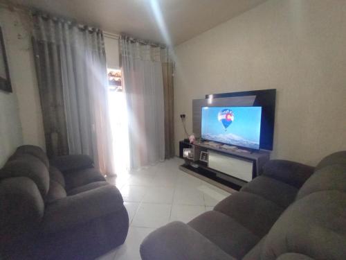 Una sala de estar con dos sofás y un televisor de pantalla plana. en Residencial Roseleia, en Penha