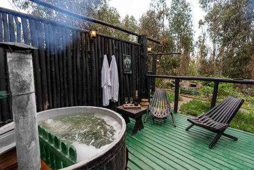 a hot tub on a deck with a bench and a chair at Bosques de San José Lodge in Algarrobo