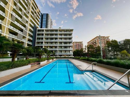 a large swimming pool in front of a building at Cosy 2-Bedroom Apartment, Homebush NSW 2140 in Sydney