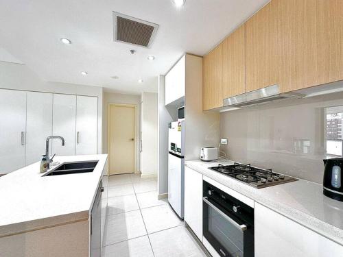 a kitchen with a sink and a stove top oven at Cosy 2-Bedroom Apartment, Homebush NSW 2140 in Sydney