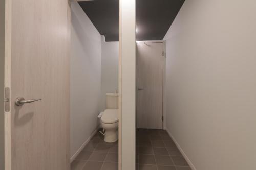 a small bathroom with a toilet and a door at 料理旅館ゆり野 in Wajiki