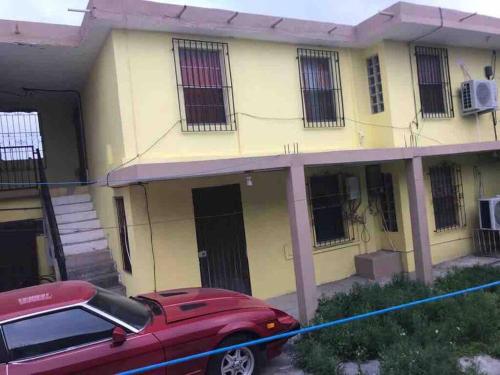 a red car parked in front of a yellow house at DptoCéntricoEntrePtesInternacionales WiFi AC TV in Matamoros