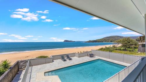 an oceanfront home with a swimming pool and a beach at Coral Sea in Pearl Beach