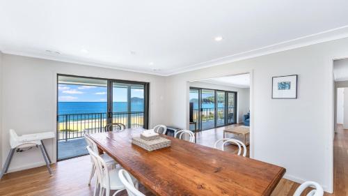 a dining room with a table and views of the ocean at Coral Sea in Pearl Beach