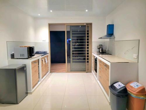 a large kitchen with white counters and appliances at Logement de charme, au soleil et proche de la mer in Moorea
