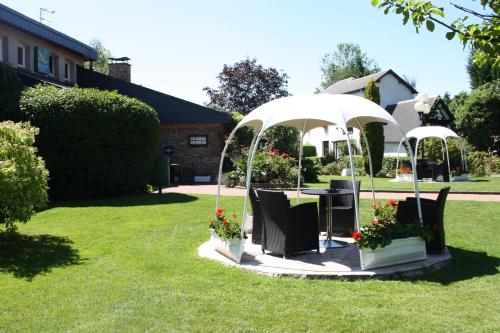 a garden with a table and chairs under an umbrella at La Berteliere, The Originals Relais in Saint-Martin-du-Vivier