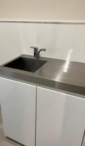 a kitchen counter with a sink and white cabinets at Restmance Pension Woody Hill in Iiyama