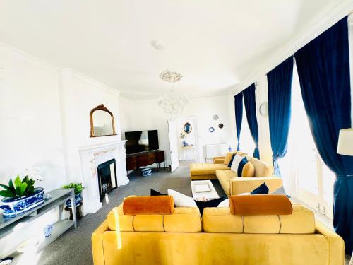 a living room with two yellow couches and a fireplace at Flat 3 Marine Parade House, 1 East Cliff - Next to Dover Port, White Cliffs, Beach, Castle in Dover