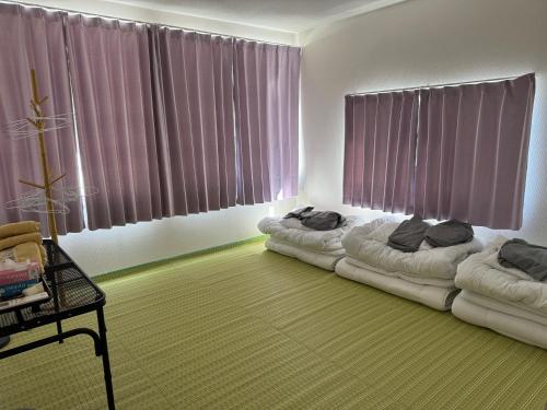 a living room with two beds in front of windows at Self check-in Hostel 5mins from JR Nishi Hiro station in Hiroshima