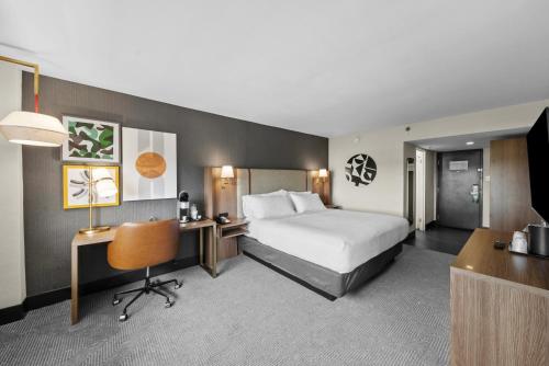 a hotel room with a bed and a desk and a chair at Holiday Inn Niagara Falls State Park Entry by IHG in Niagara Falls