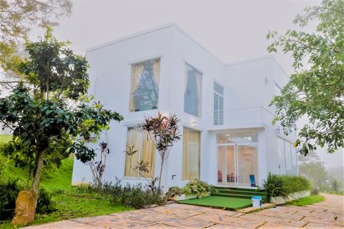 a white house with trees in front of it at Du Lịch Lâm Hà - Hồ Gia Trang Villas in Lam Ha