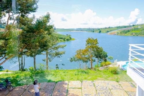 a woman is standing next to a river at Du Lịch Lâm Hà - Hồ Gia Trang Villas in Lam Ha