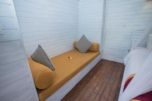 a small room with a bench with two pillows at Koji Garden Huts in Nusa Lembongan