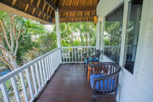 a porch with two chairs sitting on it at Koji Garden Huts in Nusa Lembongan