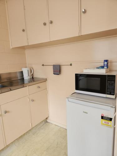 a kitchen with a microwave on top of a refrigerator at Cedar Lodge Motel Hamilton in Hamilton