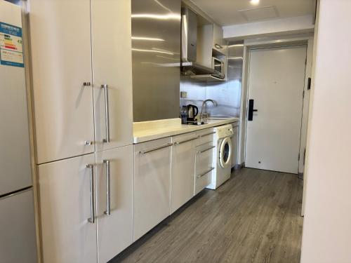 a kitchen with white cabinets and a washer and dryer at Orange International Hotel Guangzhou Zhujiang New Town US Consulate General Guangzhou Branch - Free Shuttle Bus to Canton Fair Complex During Canton Fair Period in Guangzhou