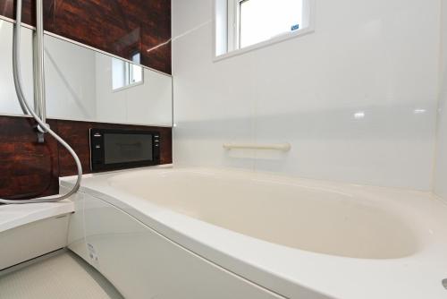 a white bathroom with a tub and a tv at Teinehoncho Ikkenya in Sapporo
