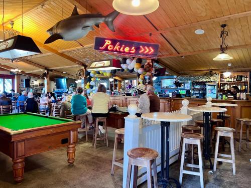 a restaurant with a pool table and people sitting at tables at 'Noni's House' Coastal Opononi Hokianga in Opononi