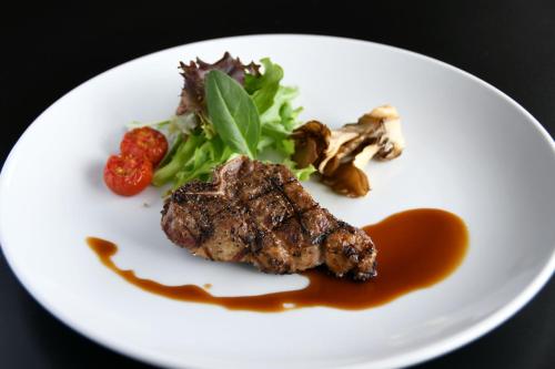 a white plate with a piece of meat and vegetables at Hotel Marroad Hakone in Hakone