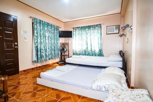 two beds in a room with blue curtains at Gracias Inn Boracay in Boracay