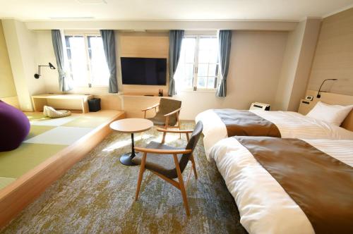 a hotel room with two beds and a living room at Hotel Marroad Hakone in Hakone