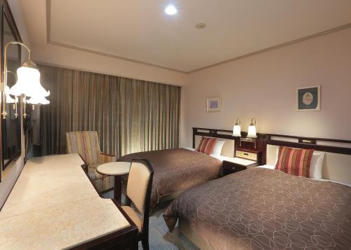 a hotel room with two beds and a table at Sasebo Washington Hotel in Sasebo