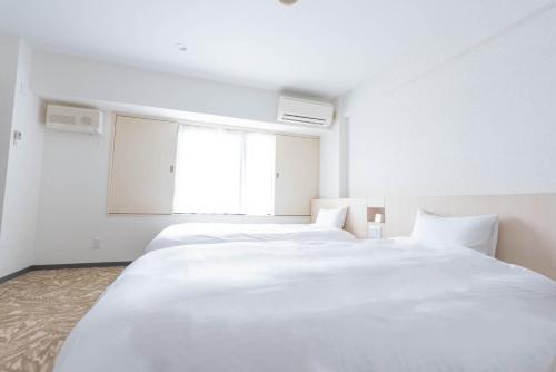 a bedroom with two white beds and a window at Hotel Alpha Inn Akita - Vacation STAY 67275v in Akita