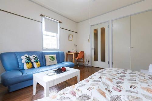 Una sala de estar con un sofá azul y una cama. en JR西国分寺駅徒歩2分 Very easy access長期間滞在歓迎, en Kokubunji