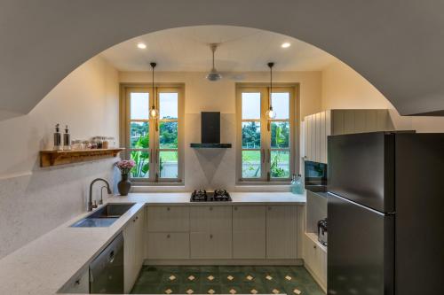 a kitchen with an archway over a sink and a refrigerator at La Rozalia, Exquisite 4 BHK Villas with Large Pool, Garden, Dedicated Caretaker, Terrace, 2 mins from the famous Dear Zindagi Road in Mapusa