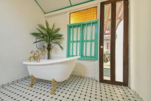 a bathroom with a tub and a palm tree in it at Ohana House @ 15 Kuli in Melaka