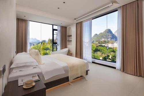 a bedroom with a large bed and large windows at THAT MAY Hotel in Yangshuo