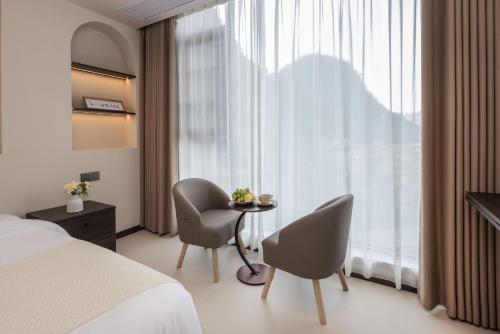 a bedroom with a bed and two chairs and a table at THAT MAY Hotel in Yangshuo
