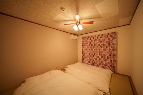 a bedroom with a ceiling fan and a bed at Takachiho Sanso Amaterasu Kagura in Takachiho