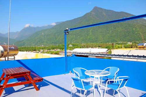 Un balcón con mesa y sillas y montañas. en 花蓮嵐海民宿, en Xincheng