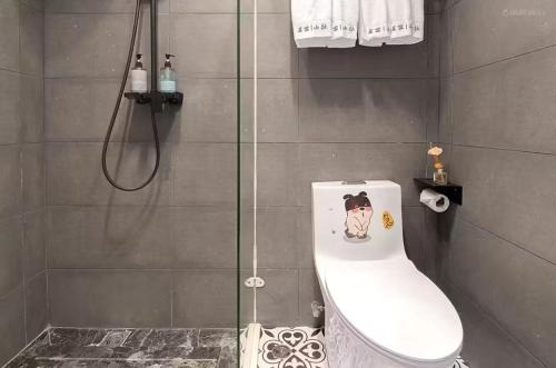 a bathroom with a shower with a toilet with a sticker on it at Xiamen Mingshu Shanqiu Homestay in Xiamen