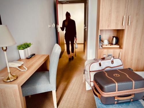 kobieta wchodząca do pokoju z walizką w obiekcie Hotel Arkadia Jelcz-Laskowice w mieście Jelcz